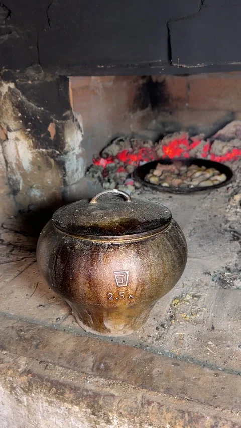 A man uses a stove hook to remove a cast iron pot with potatoes from the st.. Video stock 327554081