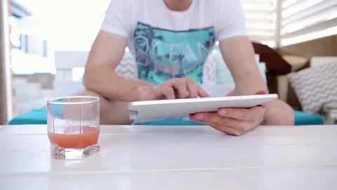 Man Uses a Tablet And Drinks Juice  Stock Footage 82442503