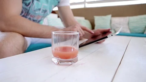 Man Uses a Tablet And Drinks Juice Stock Footage 82442569