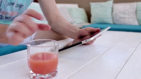 Man Uses a Tablet And Drinks Juice Stock Footage 82442578