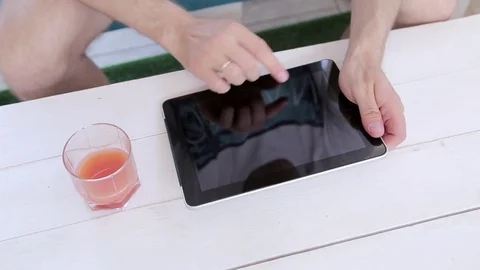 Man Uses a Tablet And Drinks Juice  Stock Footage 82442580