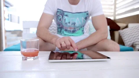 Man Uses a Tablet And Drinks Juice  Stock Footage 82442588