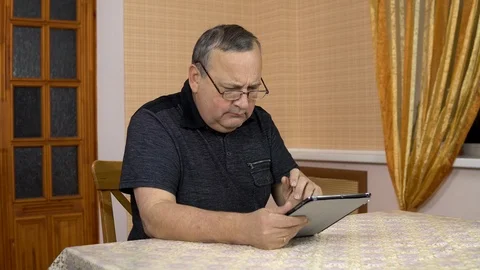 A man uses a tablet for the first time. The old man does not understand how to Stock Footage 124656525