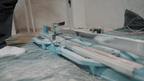 Man uses tile cutter tool to install floor tiles in a room Stock-Footage 317377462