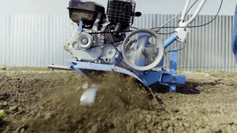 Man uses tiller to prepare backyard soil for planting Stock Footage 271630150