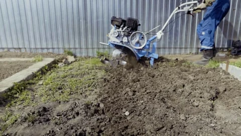 Man uses tiller to prepare backyard soil for planting Stock Footage 305188181