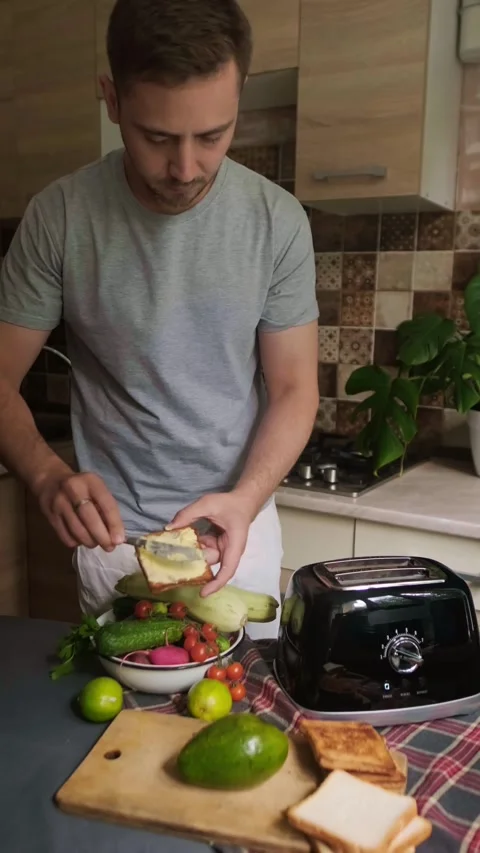 Man uses toaster to quickly prepare healthy breakfast with vegetables and greens Stock Footage 311865719