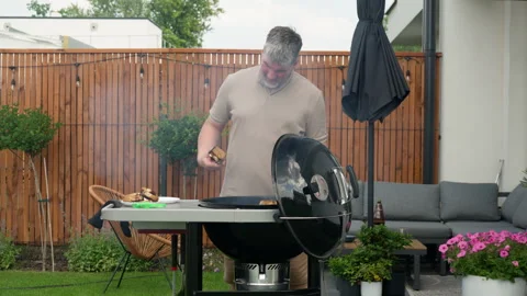 A man uses tongs to move toasted bread onto a plate from a charcoal grill Stock Footage 340163676