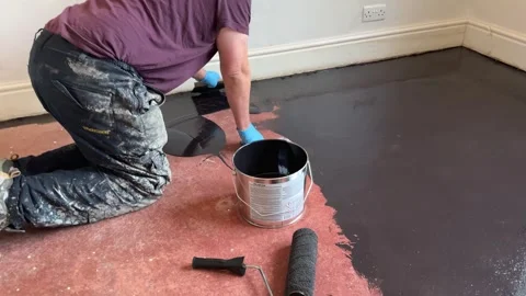 Man uses a trowel to apply damp proof membrane coating to a floor Stock Footage 293000120
