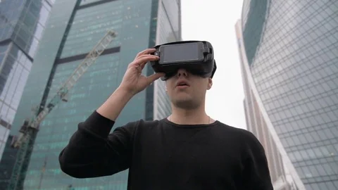 Man uses a virtual reality glasses against the skyscrapers sky Stock Footage 73910188