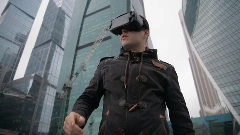 Man uses a virtual reality glasses against the skyscrapers sky Video stock 76615001