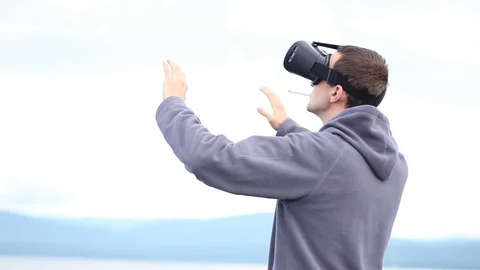Man uses a virtual reality glasses and smokes a cigarette against the sky and Stock Footage