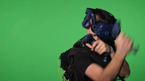 A man uses virtual reality glasses to play in a studio on a green background. Stock Footage 316592525
