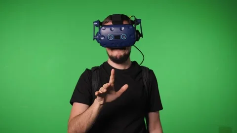 A man uses virtual reality glasses to play in a studio on a green background. Stock Footage 317300132