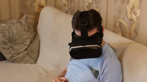 Man uses a virtual reality helmet. Sitting on the couch Stock Footage 72582639