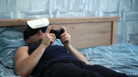 Man uses vr glasses playing games while lying on bed Stock Footage 149100974
