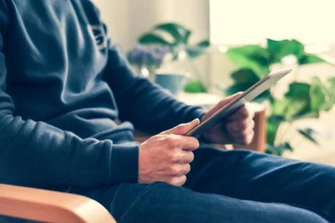 A man uses a wireless tablet device at home to check email and social media m Stock Photos