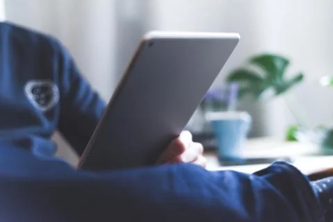 A man uses a wireless tablet device at home to check email and social media m Stock Photos