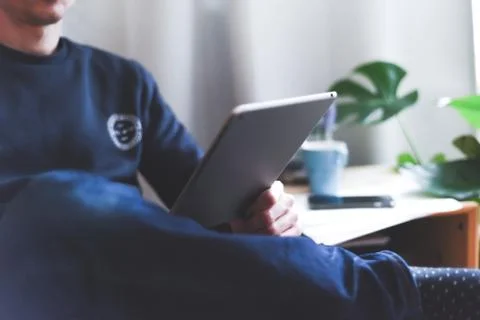 A man uses a wireless tablet device at home to check email and social media m Stock Photos