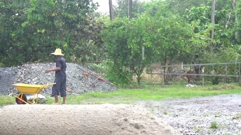 A man uses a yellow Wheelbarrow to work in the rain. Stock Footage 135897841