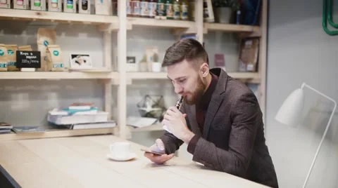 Man using an advanced personal e-cigarette and used phone Stock Footage 57114641