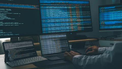 Man using AI chatbot while coding at a multi monitor workstation with lapto.. Stock Photos