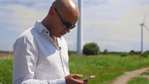 Man using and scrolling phone on the background of the a country road summer Stock Footage 115133278