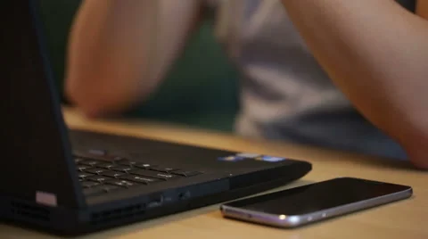 Man using and typing on a laptop by a glass of juice. Video stock 51709314