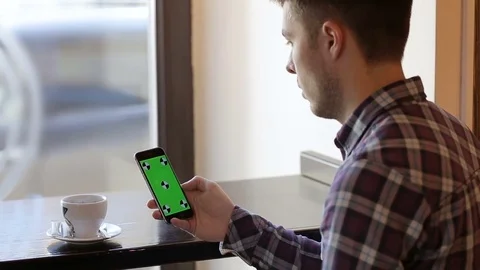 Man using app on mobile cell phone with green touch screen in cafe Stock Footage 73020800