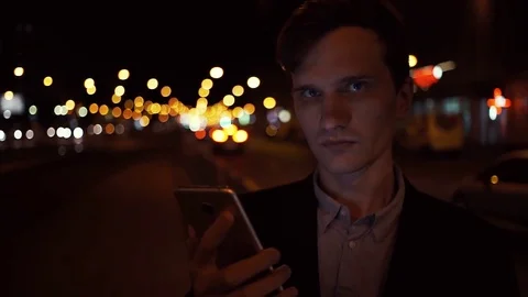 Man using app on smart phone at night. Cars and defocused lights at background Stock Footage 80009503