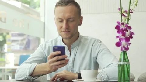 Man using app on smartphone drinking coffee, texting on mobile phone Video stock 79045986