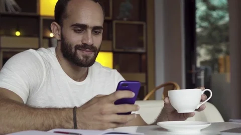 Man using app on smartphone drinking coffee, texting on mobile phone Stock Footage 83719111