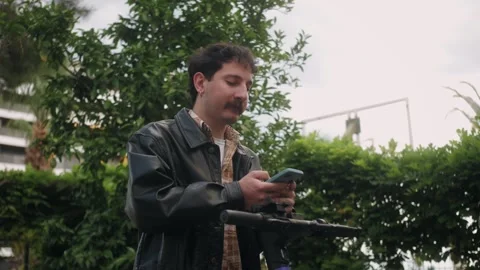 Man using app on smartphone to unlock electric scooter on the street. Urban Stock Footage 277684928