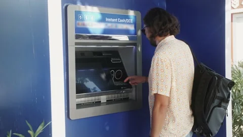 Man using ATM machine withdraw cash outdoor. Inserting card in ATM machine. 库存影片 220941093