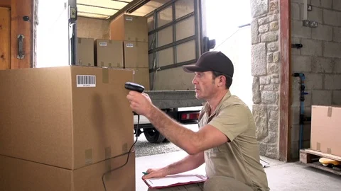 Man using a barcode scanner &amp; clipboard with parcels in the warehouse Stock Footage 125133167