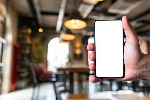 Man using bezel less smart phone in a restaurant. Stock Photos