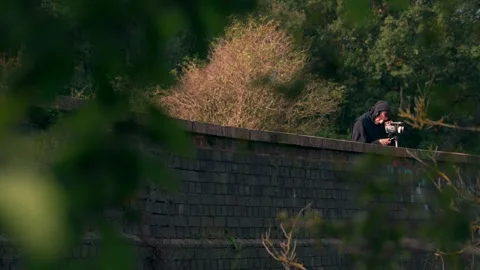 A man using a big old camera on an old brick bridge in England 스톡 동영상 347868630