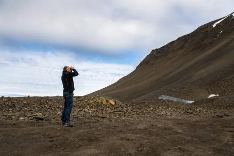 Man using binoculars in the mountains at Svalbard Stock Photos
