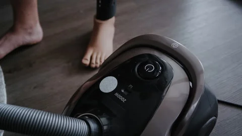 Man Using Bionic Leg to Turn On Vacuum Cleaner at Home Stockbeeldmateriaal 317973693