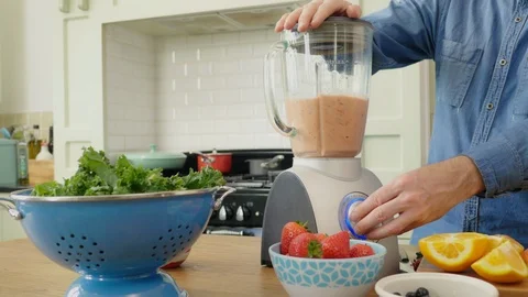 Man Using Blender By Various Fruits And Vegetable At Table Stock Footage 86073979