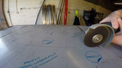 A man using a Bosch Grinder with a cutting disc to cut sheet metal at an Video stock 101713913