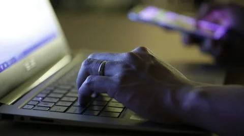 Man using both laptop and smartphone at night in a dark space. Stock Footage 51709353