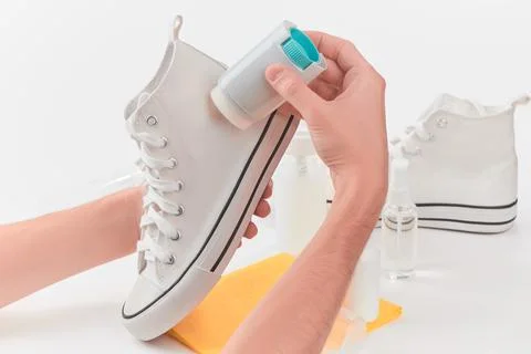 Man using a brightening agent on a canvas sneaker to give them a fresh look Stock Photos