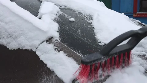 A man using a brush to clean the car from snow in winter in cold weather Stock Footage 173093540