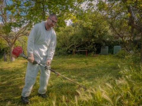 Man using brush cutter Stock Photos