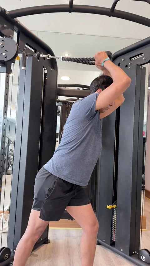 Man Using Cable Machine for Triceps Pushdown Exercise in Indoor Gym Stock Footage 342351748