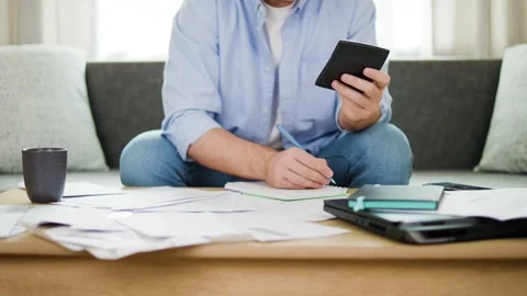Man using calculator and writing in notebook to budget home expenses, pay utilit Stock Footage 342599274