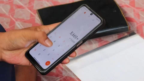 Man using a calculator app on a smartphone for financial management Stock Footage 336295078