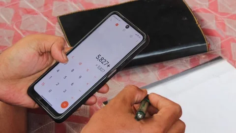 Man using a calculator app on a smartphone for financial management Stock Footage 336295085