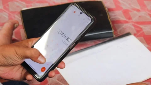 Man using a calculator app on a smartphone for financial management Stock Footage 336295086